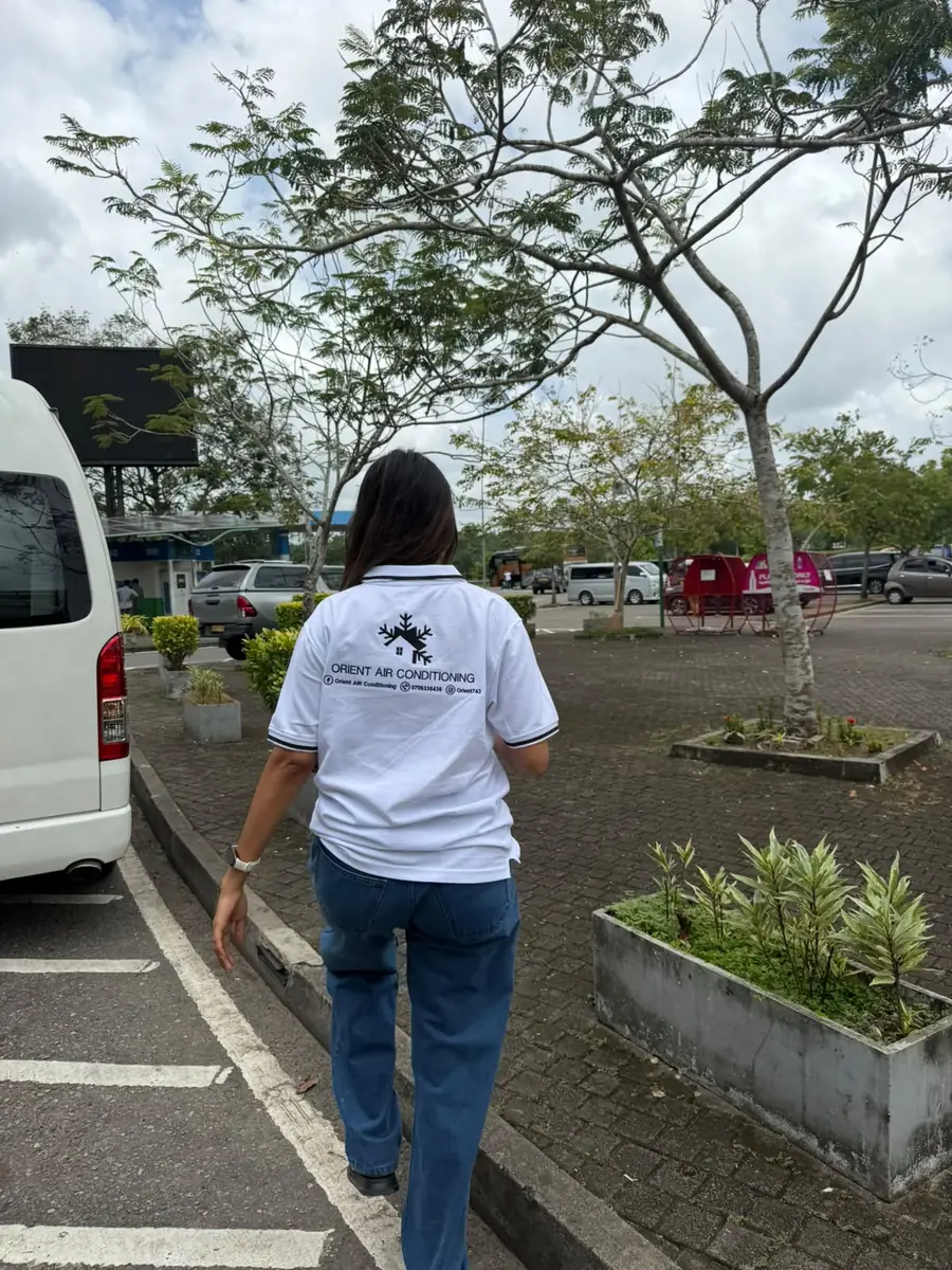 An Orient Air Conditioning team member in the company shirt walking across a car park to a job