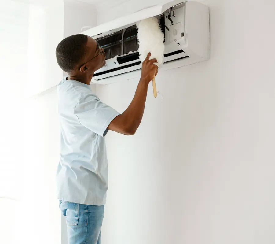Technician cleaning the inside of a wall-mounted air conditioner