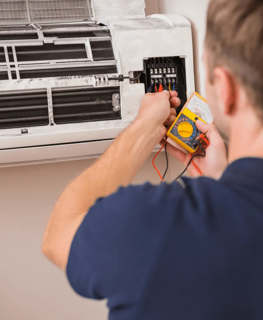 Technician testing the wiring of a wall-mounted air conditioner with a multimeter