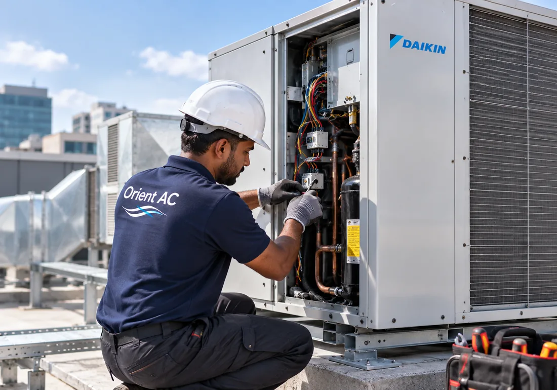 Orient AC technician working on a bank of rooftop industrial condenser units